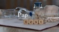 Words PAP TEST composed of wooden dices. Pills, documents and a pen in the background