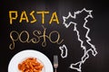 Words pasta made of cooked spaghetti and dry pasta on the black background with frame of country Italy written by chalk Royalty Free Stock Photo