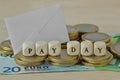 Words Pay day written with wood cubes over euro coins and banknotes