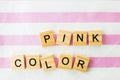 Words pink color written in cubic letters on a pink striped textiles background, selective focus