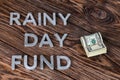 The words RAINY DAY FUND near small pack of us dollars on wooden background