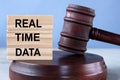 The words REAL TIME DATA on wooden cubes against the background of the judge\'s gavel and stand