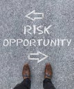 Words Risk, Opportunity and arrows written on the ground in front of a man's shoes Royalty Free Stock Photo