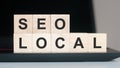 The words SEO LOCAL in wooden cubes on the computer keyboard Royalty Free Stock Photo