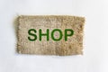 The words Shop written on burlap and a white background