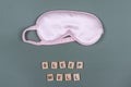 Words SLEEP WELL and pink sleeping eye mask, top view. Good night, flight and travel concept. Sweet dreams, relax, siesta, Royalty Free Stock Photo