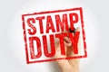 The words STAMP DUTY appear in a distressed red rectangular stamp style while a hand with a marker appears to be drawing it. The Royalty Free Stock Photo