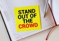 The words Stand out of the crowd written on a white notebook. Closeup of a personal agenda Royalty Free Stock Photo