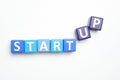 Words START UP made with color cubes on white background, flat lay