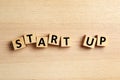 Words START UP made with cubes on wooden background, flat lay