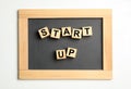 Words START UP made with wooden cubes and chalkboard on white background
