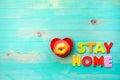 Words STAY HOME and apple in heart shape plate on wooden background