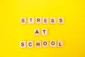 Words stress at school. Wooden blocks with an inscription on top on a yellow background. Social problems of teenagers and children