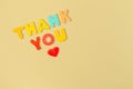 Words THANK YOU and red heart on wood letters on yellow background