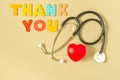 Words THANK YOU, stethoscope and red heart on yellow background