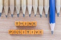 Words Think Positive on wooden table with group of pencils.