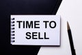 The words TIME TO SELL written in red on a black and white background near the pen