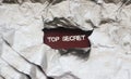 The words Top secret appearing behind torn foil