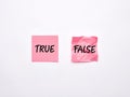 The words true and false on pink sheets of note paper on white background. Exam or true information concept Royalty Free Stock Photo