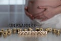 Words UNPLANNED PREGNANCY composed of wooden letters