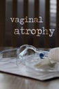 Words VAGINAL ATROPHY. Plastic vaginal speculum, pills and other tools in the background