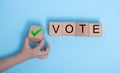 The words VOTE on wooden cubes. The concept of choosing the right solution. Child`s hand holds a block, makes a choice, votes for Royalty Free Stock Photo