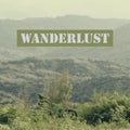 Words `Wanderlust` on mountain background.