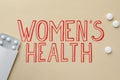 Words Women`s Health and pills on beige background, flat lay