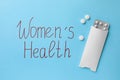 Words Women`s Health and pills on light blue background, flat lay