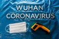 Words wuhan coronavirus laid with metal letters on crumpled blue plastic film backdrop with face masks and thermometer