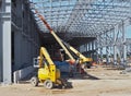 Work aerial platforms at work under a large frame for a new building under construction.