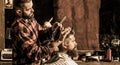 Work in the barber shop. Hairdresser cutting hair of male client. Hairstylist serving client at barber shop. Bearded man Royalty Free Stock Photo