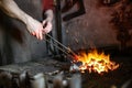 blacksmith holds red-hot metal by tongs in the forge furnace Royalty Free Stock Photo