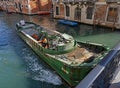 A work boat on a canal in Venice, Italy is equipped with a hydraulic boom crane.