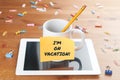 Work and business concept: a cup with a pencil inside on a tablet with a memo and the text I`m on vacation Royalty Free Stock Photo