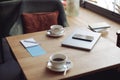 Work in cafe. Table with two white coffee cups and business stuff. Cozy place. laptop and smartphone