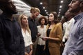 Work colleagues stand waiting together in an elevator at their office