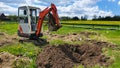 Work on the construction site of a house. The excavator digs out roots. A small digger in the garden Royalty Free Stock Photo