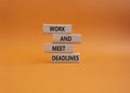 Work and deadline symbol. Concept words Work and meet deadlines on wooden blocks. Beautiful orange background. Business and Work