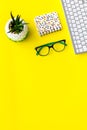 Work desk of creative person. Computer keyboard, glasses, bright stationery, plant on yellow background top view space Royalty Free Stock Photo