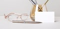 Work desk with golden glasses, pen, white blank card with place to insert text. Business template. Home Office. Workplace close up Royalty Free Stock Photo