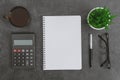 Work desk with notebook, calculator, coffee cup, eyeglasses pen and potted plant