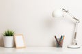 A work desk with a white lamp, a pencil stand, a frame and a home plant. The concept of modern space Royalty Free Stock Photo