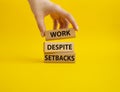 Work despite setbacks symbol. Wooden blocks with words Work despite setbacks. Beautiful yellow background. Businessman hand.