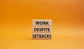 Work despite setbacks symbol. Wooden blocks with words Work despite setbacks. Beautiful orange background. Business and Work