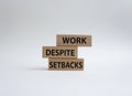 Work despite setbacks symbol. Wooden blocks with words Work despite setbacks. Beautiful white background. Business and Work