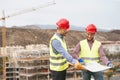 Work engineers discussing about new building area - Young builders reading the project in the construction site Royalty Free Stock Photo