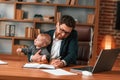 Work and family. Businessman in formal clothes is indoors. With toddler Royalty Free Stock Photo