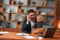 Work and family. Businessman in formal clothes is indoors. With toddler Royalty Free Stock Photo