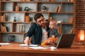 Work and family. Businessman in formal clothes is indoors. With toddler Royalty Free Stock Photo